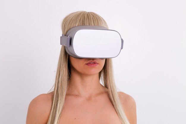 Portrait of topless woman in virtual reality glasses, studio shot, white.