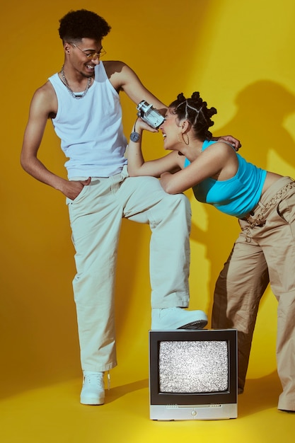 Free Photo portrait of two friends in 2000s fashion style posing together with tv and camera