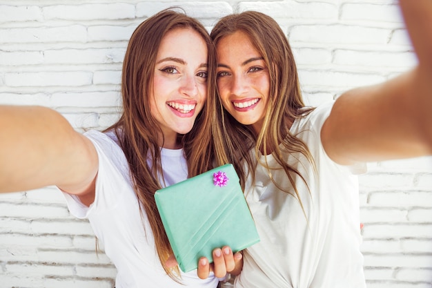 Portrait of two happy female friends with gift box