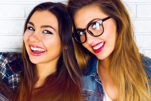 Portrait of two pretty teen girlfriends smiling and posing