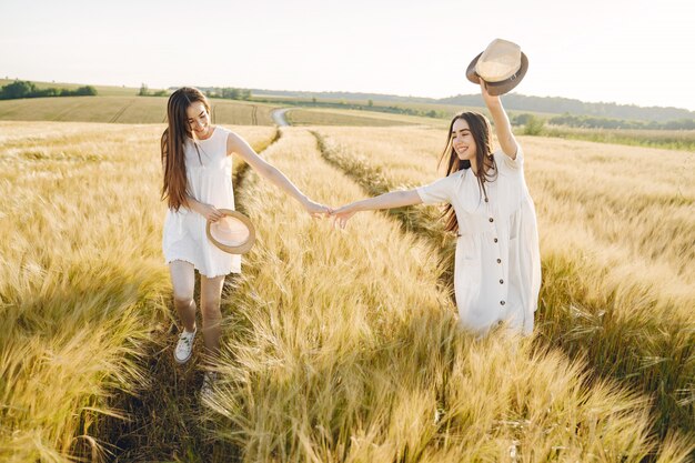 Portrait of two sisters in white dresses with long hair in a field