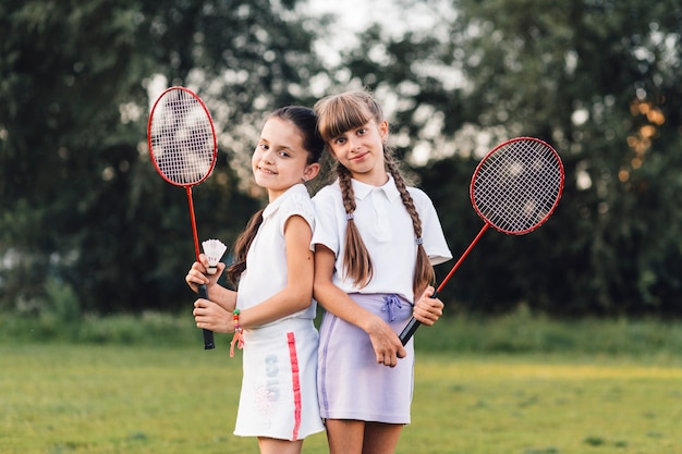 Portrait of two smiling girls holding shuttlecock and badminton in hand