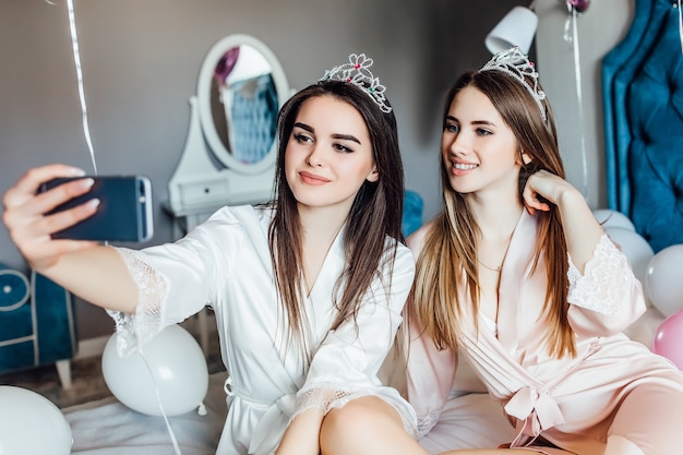 Free Photo portrait of two woman make selfie at bedroom, have a good hen party