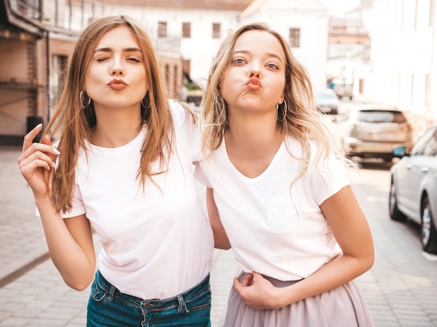 Free Photo portrait of two young beautiful blond smiling hipster girls in trendy summer white t-shirt clothes.  . positive models makes duck face