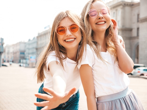 Free Photo portrait of two young beautiful blond smiling hipster girls in trendy summer white t-shirt clothes.  