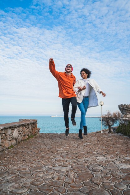 Portrait of two young friends spending some nice time together, walking on coast line and having fun.