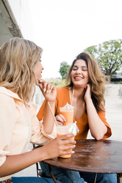 Free photo portrait of two young friends spending time together at a coffee shop outdoors. urban concept.