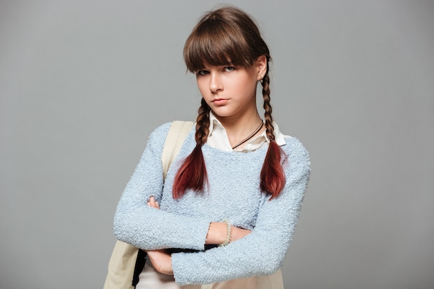 Free photo portrait of an upset sad schoolgirl standing with arms folded