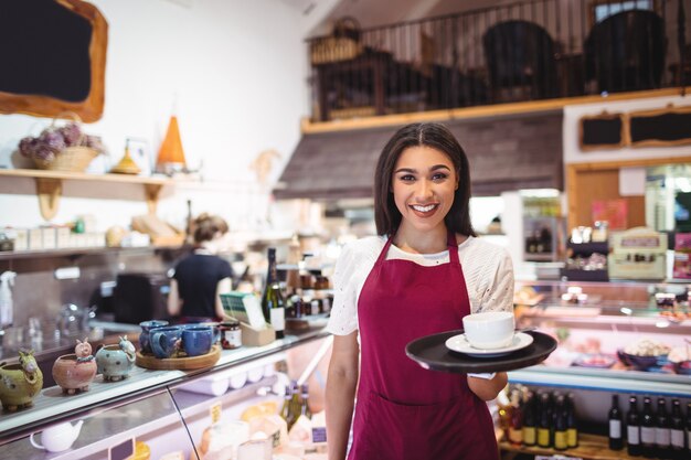 Portrait of waitress serving a cup of coffee