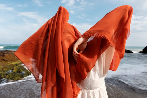 Free Photo portrait of woman at the beach covering her face with veil