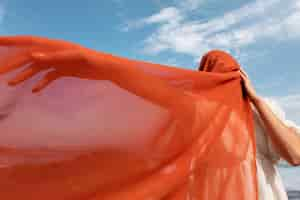 Free photo portrait of woman at the beach covering her face with veil