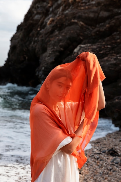 Free photo portrait of woman at the beach covering her face with veil