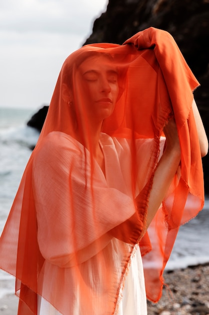 Free Photo portrait of woman at the beach covering her face with veil