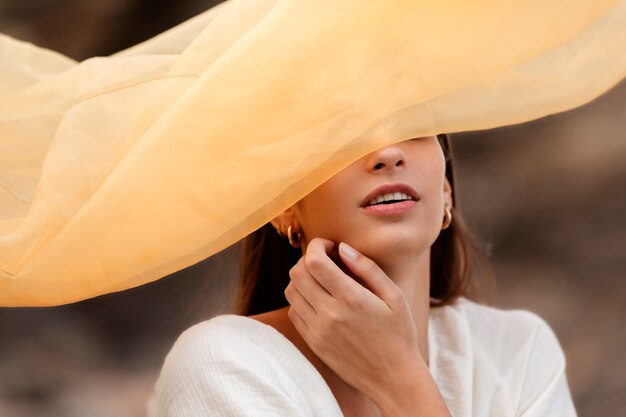 Free photo portrait of woman at the beach hiding her face behind veil