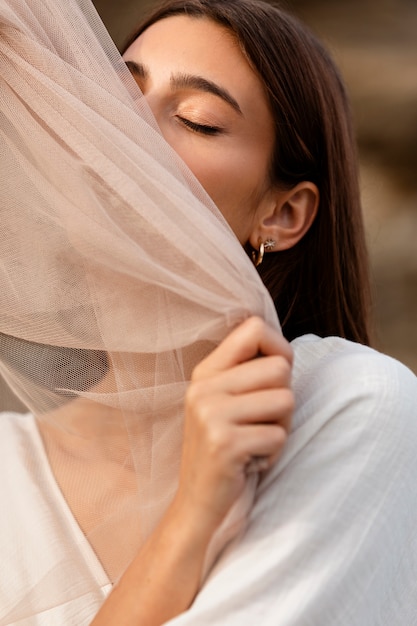 Free photo portrait of woman at the beach hiding her face behind veil