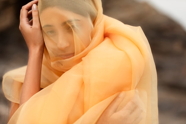 Portrait of woman at the beach with face covered by veil