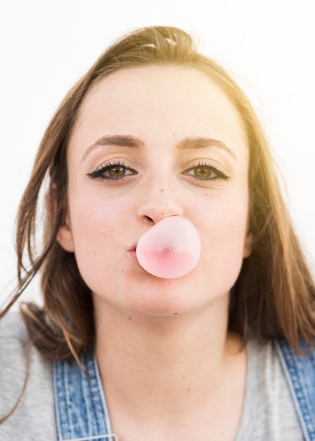 Free photo portrait of a woman blowing bubble gum looking at camera