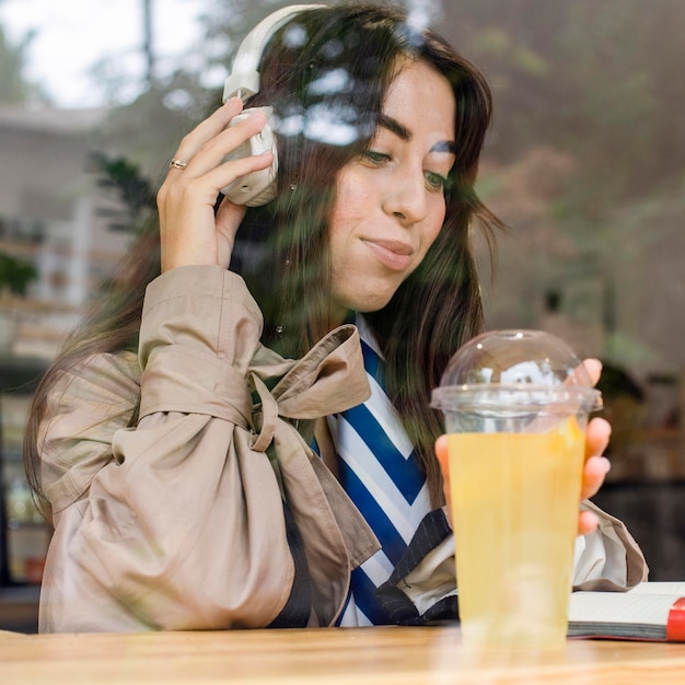 Free photo portrait of woman in cafe with fresh lemonade and headphones