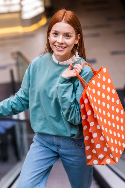 Portrait of woman climbing escalator and holding shopping bag