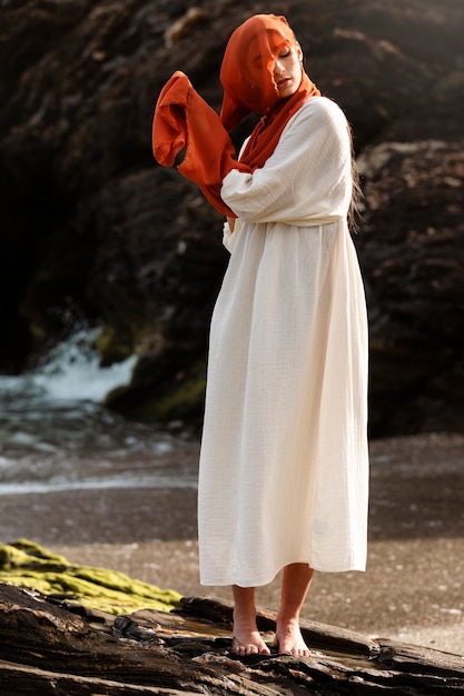 Free photo portrait of woman covering her face with veil at the beach