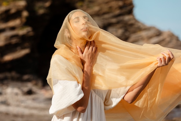 Free photo portrait of woman covering her face with veil at the beach