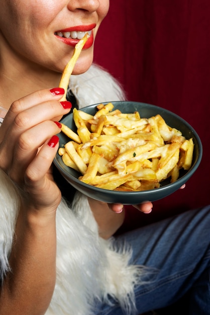 Free Photo portrait of woman eating a dish of poutine