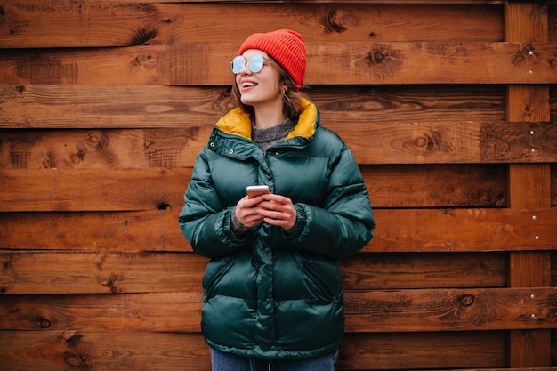 Free Photo portrait of woman in emerald green coat on wooden wall