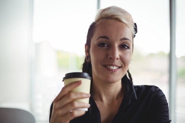 Portrait of woman holding disposable coffee cup