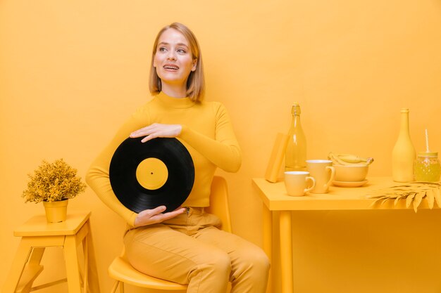 Portrait of woman holding a vinyl in a yellow scene