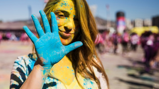 Portrait of a woman looking at camera showing painted blue hand