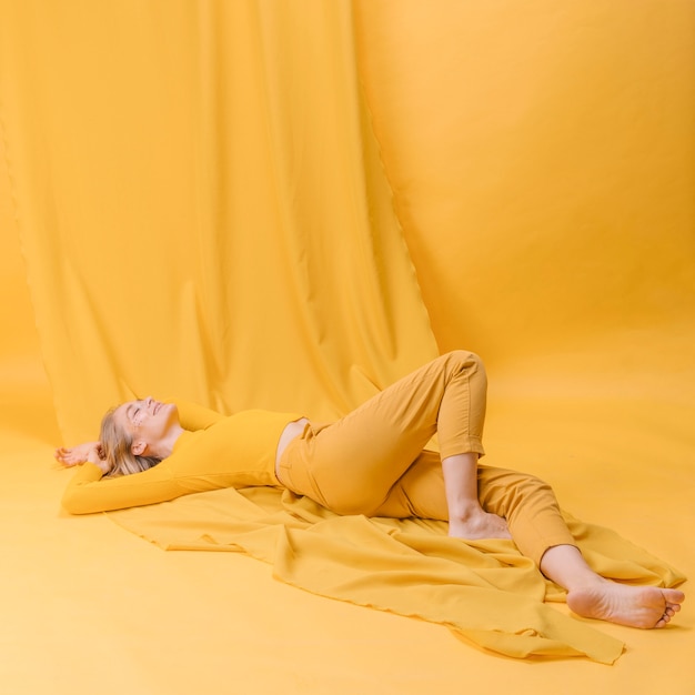 Free photo portrait of woman lying in a yellow scene