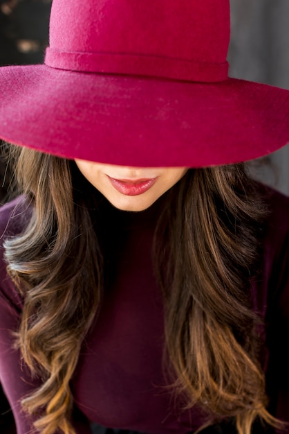 Portrait of a woman in pink hat covering her eyes