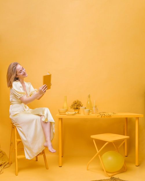 Free Photo portrait of woman reading a book in a yellow scene