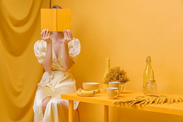 Free photo portrait of woman reading a book in a yellow scene