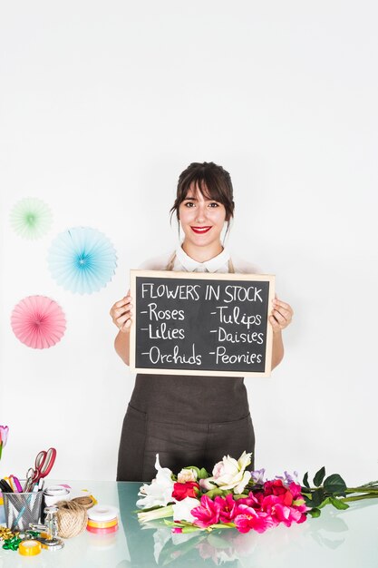 Portrait of a woman showing flowers in stock on slate