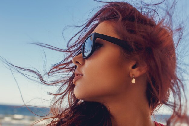 Portrait of a woman in sunglasses with long brown hair.