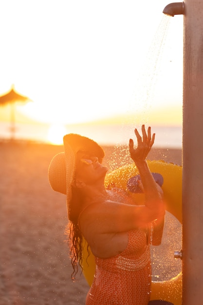 Free photo portrait of woman taking a shower on the beach