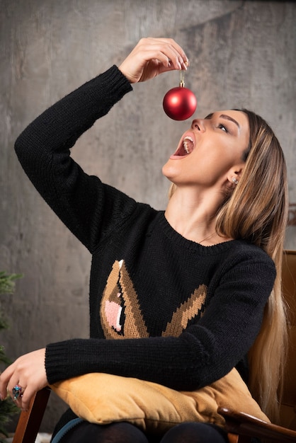 Free Photo portrait of woman trying to eat shiny christmas ball.