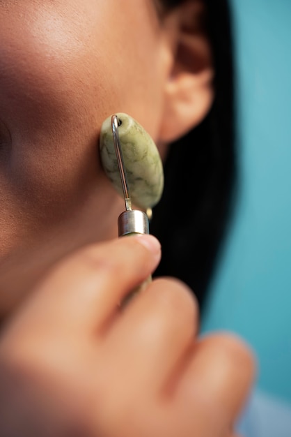 Free photo portrait of woman using jade roller on her face