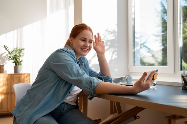 Free Photo portrait of woman using smartphone at home with pop socket