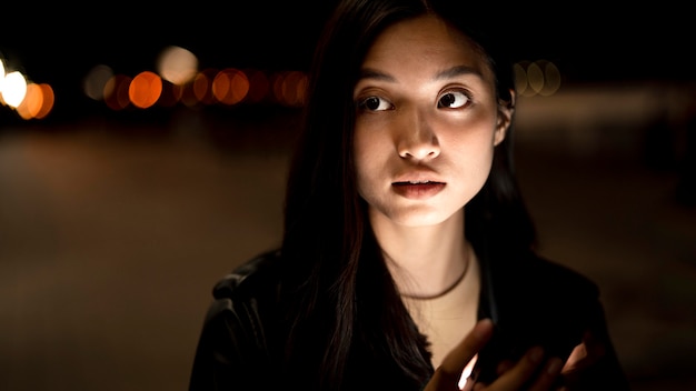 Portrait of woman using smartphone at night in the city lights