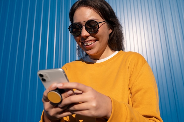 Portrait of woman using smartphone with pop socket outdoors