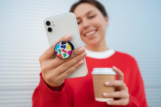 Free photo portrait of woman using smartphone with pop socket outdoors