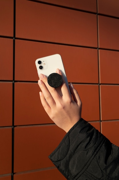 Free photo portrait of woman using smartphone with pop socket outdoors