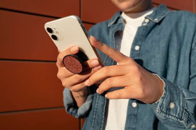 Free photo portrait of woman using smartphone with pop socket outdoors