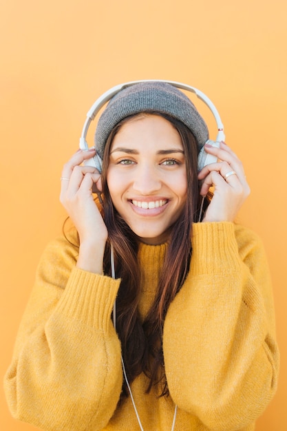 Free Photo portrait of a woman wearing headphones against colored surface