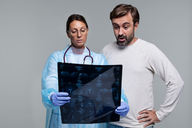 Free photo portrait of woman wearing medical gown showing patient ct scan