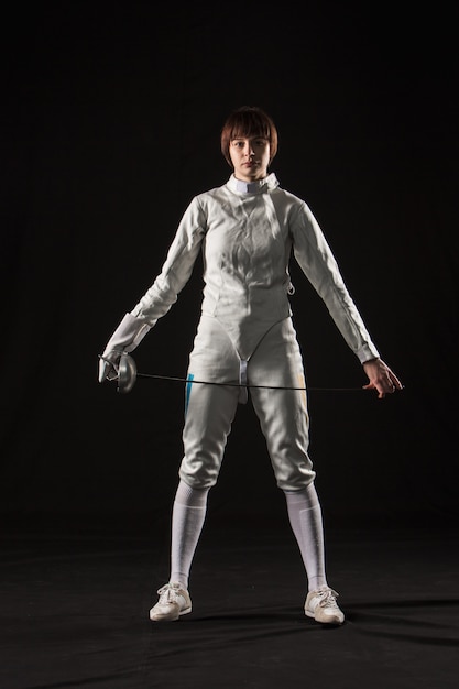 Free photo the portrait of woman wearing white fencing costume on black