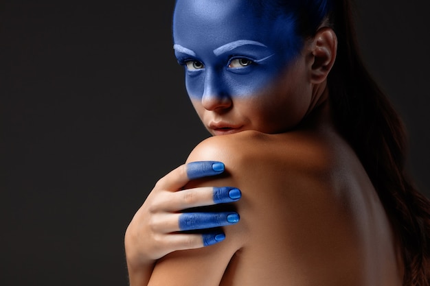 Free photo portrait of a woman who is posing covered with blue paint