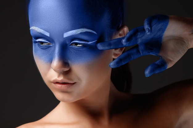 Portrait of a woman who is posing covered with blue paint